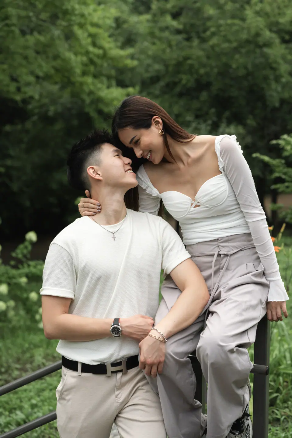 A couple embracing on a railing among green trees