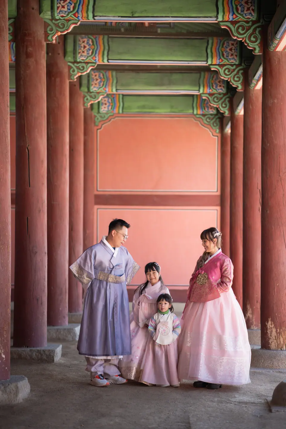 A family in hanbok under the painted eaves of a palace