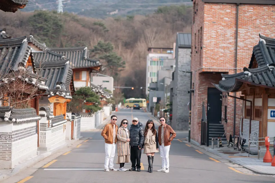 A group walking a street lined with hanok and brick buildings