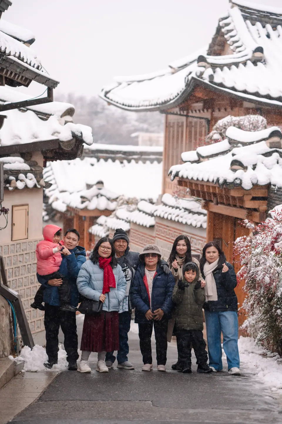 A family standing in the snow in a hanok alley