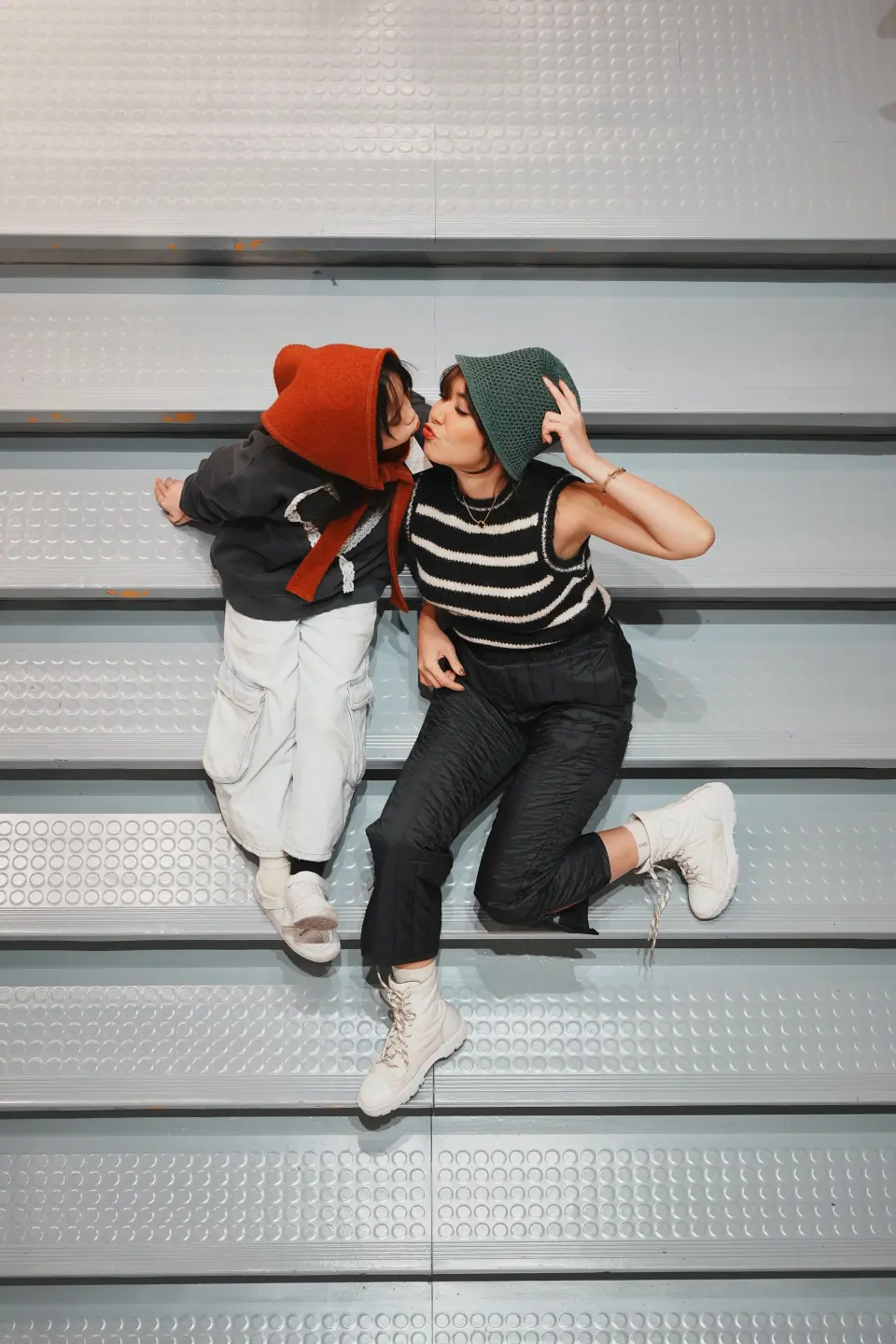 A mother and daughter lying on grey steps, seen from above